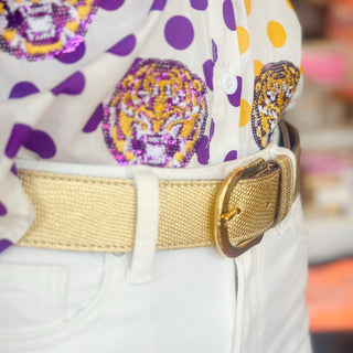 Amsterdam Heritage Dana gold metallic leather belt styled with white pants and a purple and gold game day top, close-up view