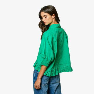 Woman wearing a green blouse with ruffled details on a white background
