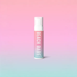 Bottle of Sugar Glow Beach Babe self-tanning mousse in a pink ombré design with white pump top, photographed against a pastel background.