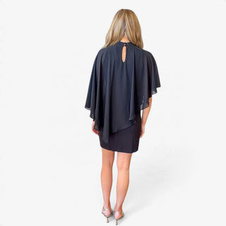 Black cape overlay mini dress featuring a sheer draped back, high neckline with keyhole closure and fitted mini skirt, full back view.