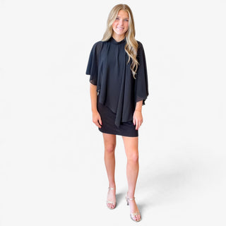 Black sheer cape overlay mini dress with a high neckline, flowing chiffon-style sleeves and fitted skirt, front view styled with silver heels.