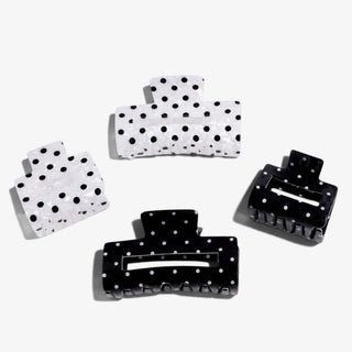 Polka dot hair claw clips in pearl white and black, in small and standard sizes on a white background