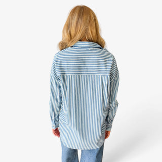 Blue and white striped button down shirt for women showing a horizontal striped back yoke, vertical stripes, relaxed silhouette, and rounded hem, back view.