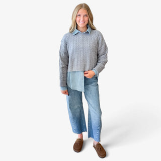 Blue and white striped button down shirt for women styled beneath a cropped gray cable knit sweater, showing the striped collar, cuffs, and hem, front view.