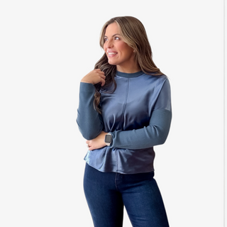 Woman wearing a blue long-sleeve top and jeans on a white background
