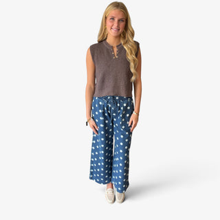 Brown cropped knit sweater vest with textured knit fabric and button neckline styled with polka dot wide leg pants, front view
