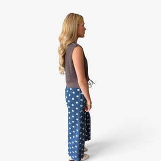Brown cropped knit sweater vest showing relaxed sleeveless fit and cropped hem styled with polka dot pants, profile view