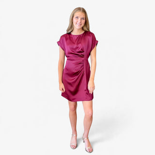 Burgundy satin mini dress featuring a softly draped bodice, gathered side detailing and short sleeves, full-length front view on model.