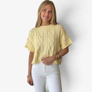 Butter yellow cable knit sweater with short sleeves and relaxed fit styled with white jeans, front tucked view