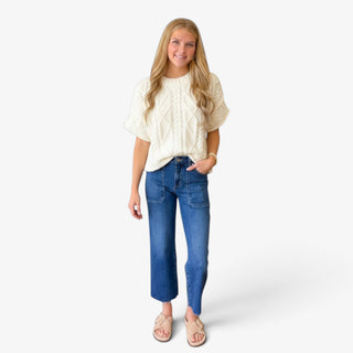 Off white cable knit sweater styled with cropped jeans, and neutral sandals  full outfit view.