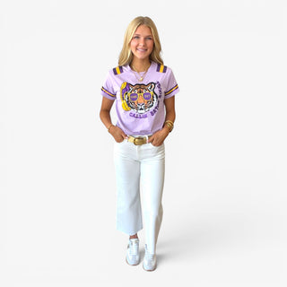 Lavender sequin game day tee with tiger graphic, purple and gold striped sleeves, and white jeans, full front view