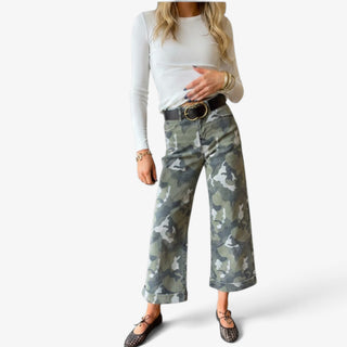 Camo cuffed wide leg jeans in green camouflage print with cropped length and wide rolled hems, styled with a white long sleeve top and flats.