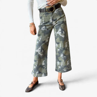 Camo cuffed wide leg jeans in green camouflage print with cropped length and wide rolled hems, styled with a white long sleeve top and flats.