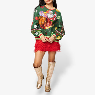 Person wearing a festive sweater with Santa Claus and holiday-themed designs, paired with a red skirt and gold boots on a white background.
