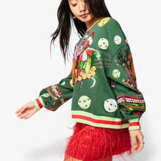 Person wearing a colorful green sweater with various patterns and a red skirt on a white background