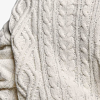 Cream cable knit sweater with brown contrast trim at neckline, cuffs and hem, styled close-up view