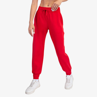 Red scuba jogger pants with elastic waistband and tapered leg styled with white sneakers