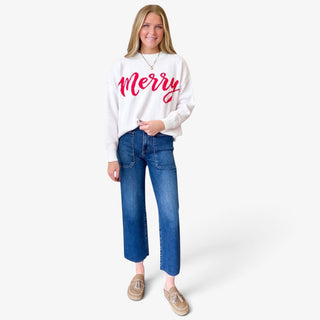 Dark wash utility wide leg jeans with cropped length and front patch pockets, styled with white Christmas sweater and tan loafers, full front view.