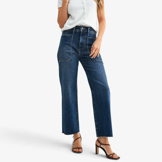 Dark wash wide leg jeans with high rise waist, front utility pockets and cropped raw hem styled with heels, angled view