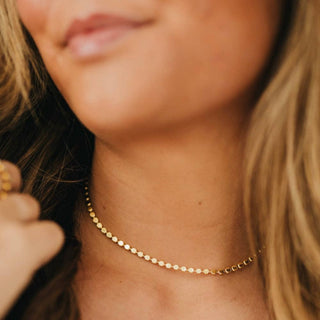 Gold disc chain necklace with adjustable extender clasp on white background product flat lay view.