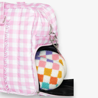 Pink checkered bag with a colorful pair of slippers inside on a white background