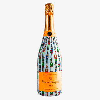 Champagne bottle wrapped in WH Hostess Nutcracker design with colorful holiday characters, fits most 750ml bottles for gifting or entertaining.