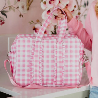 Pink checkered quilted duffle bag with ruffle trim and shoulder strap