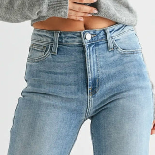 Close-up of medium wash cropped wide leg jeans showing the high rise waistband, button closure and denim wash detail