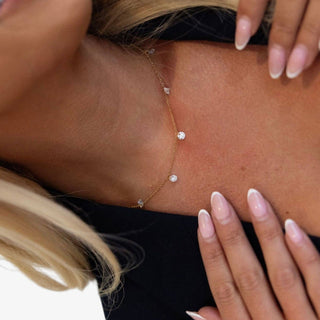 Dainty gold crystal station necklace with bezel set round stones worn layered on neckline