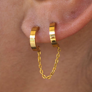Double gold hoop earrings linked with a chain on ear