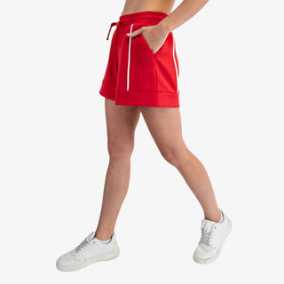 Red high waisted scuba A-line shorts with cream piping detail and drawstring waistband styled with white sneakers