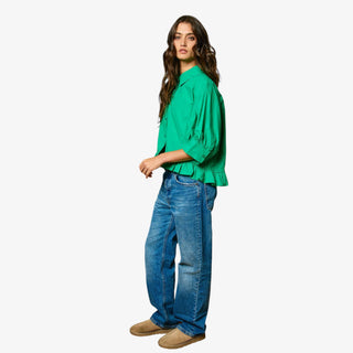 Woman wearing a green blouse and blue jeans on a white background