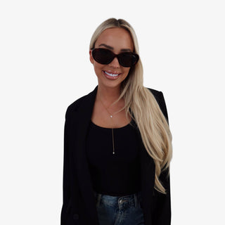 Gold lariat necklace with teardrop crystal detail worn with black top and blazer