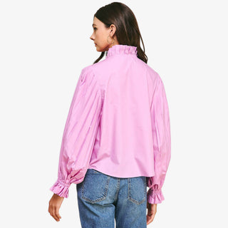 Woman wearing a pink blouse with long sleeves and blue jeans on a white background