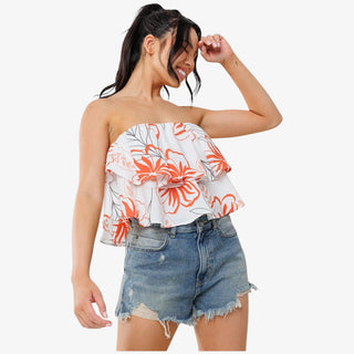Woman wearing a floral strapless top and denim shorts on a white background