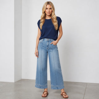 Front view of light wash front crease wide leg jeans with cropped length styled with a navy cap sleeve top.