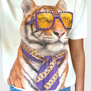 Close-up of heather cream tiger graphic tee featuring purple rhinestone sunglasses and a purple-and-gold chain-print scarf.