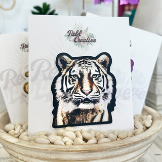 Glistening Tiger Sticker with metallic gold tiger detail displayed on product card in a neutral boutique lifestyle setting.
