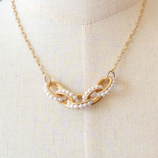 Gold pearl necklace by Kitzi Perry with interlocking gold links and pearl accents, close-up front view