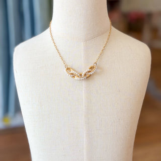 Gold pearl necklace by Kitzi Perry displayed on a cream jewelry bust, full front product view