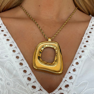 Gold statement pendant necklace with oversized geometric pendant on rope chain worn with white eyelet top front view
