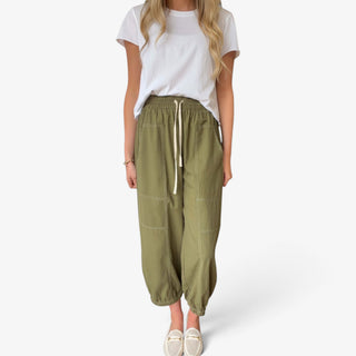 Moss green cotton balloon pants with elastic drawstring waist, contrast stitching, oversized patch pockets and gathered ankle hems, front view