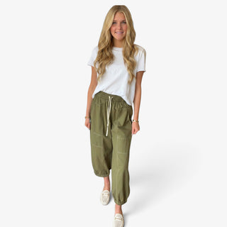 Olive green cotton balloon pants featuring a relaxed tapered silhouette, elastic drawstring waist and contrast stitching, full front view