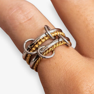 Stack of gold and silver rings on a finger against a neutral background
