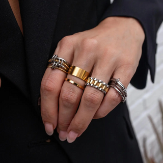 Hand wearing multiple gold and silver rings with a blurred background