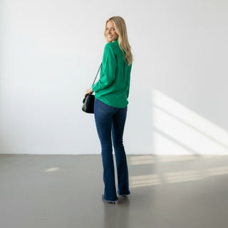 Kelly green button down blouse back angled view showing relaxed fit, curved hem, back yoke detail, and long sleeves.