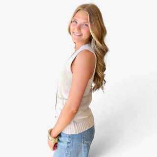 Women's khaki sleeveless sweater vest featuring a relaxed fit, textured knit fabric, and ribbed hem, side view styled with blue denim jeans.