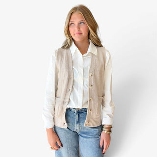 Women's khaki button front sweater vest layered over a white collared shirt, featuring a V-neckline, patch pockets, and ribbed hem, front view.
