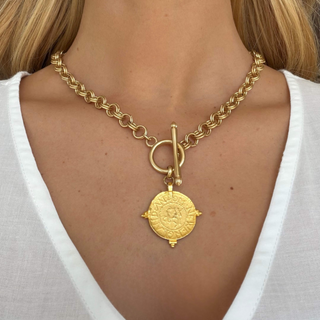 Kitzi Gold Coin Necklace with textured gold chain, toggle closure and round antique-style coin pendant, shown worn in a close-up front view