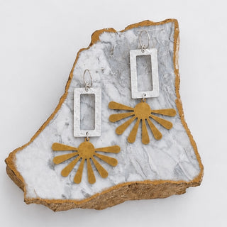 Kitzi Two Tone Sunburst Earrings with matte silver rectangular links and gold sunburst drops displayed on marble stone